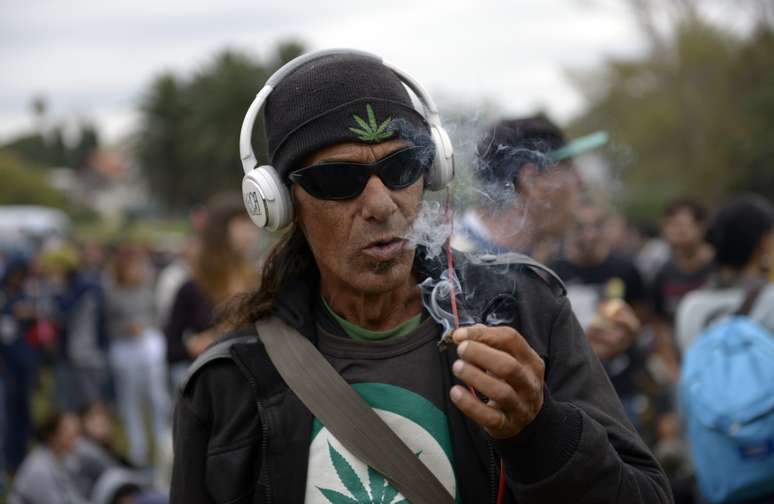 <p>Homem fuma um cigarro de maconha em um parque onde pessoas se reuniram durante a Primeira Marcha Mundial pela Maconha Regulada, em Montevidéu, neste 3 de maio</p>