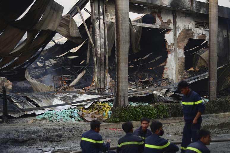 <p>Bombeiros descansam perto de uma f&aacute;brica de sapatos chinesa&nbsp;que foi danificada, no sul da prov&iacute;ncia de Binh Duong, no Vietn&atilde;, em 14 de maio</p>