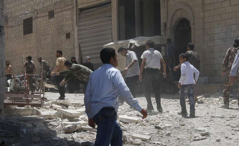 <p>Pessoas entre escombros de edifícios derrubados depois de possível ataque aéreo por forças leais ao presidente sírio, na província de Idlib </p>