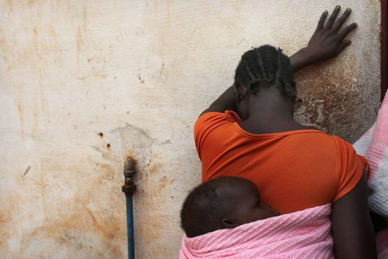 <p>(Imagem de arquivo): sudanesa segura o filho nas costas; uma mulher do país africano foi condenada à morte por se converter ao cristianismo</p>
