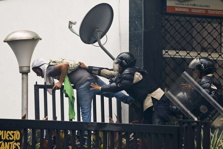 <p>Polícia nacional da Venezuela detem um manifestante anti-governo durante confrontos em Los Palos Grandes, em Caracas, na última quinta-feira, 8 de maio</p>