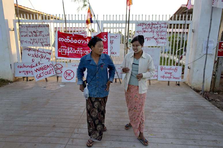 Ativistas andam ao lado de cartazes colados na entrada da empresa de mineiração chinesa em Letpadaung, Monywa em 28 novembro de 2012