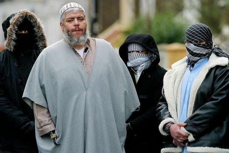 <p>Fotografia de 2003 mostra o clérigo muçulmano Abu Hamza fora da mesquita, em Londres, cercado por apoiadores</p>
