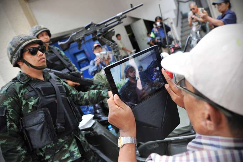 <p>Homem tirando foto de perto dos soldados nas ruas de Bangcoc, capital da Tail&acirc;ndia</p>