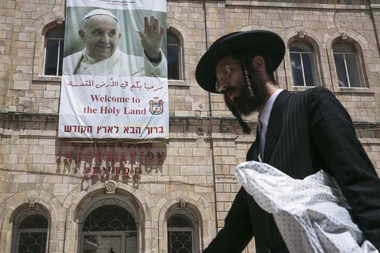 <p>Judeu ultra-ortodoxo é visto passando em frente de um cartaz em homenagem ao Papa, na Velha Jerusalém</p>