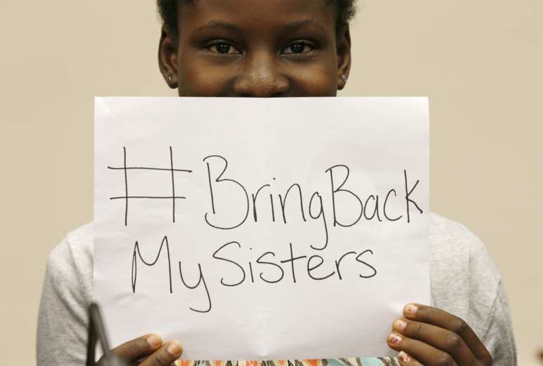 <p>A estudante Deborah Peter, sobrevivente do ataque do grupo Boko Haram em 2011, segura um cartaz escrito &quot;Traga de volta&nbsp;as minhas&nbsp;irm&atilde;s&quot;</p><p>&nbsp;</p>