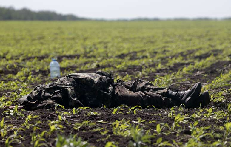 <p>Um corpo coberto com um uniforme p&ocirc;de ser fotografado em um campo perto da vila de Blahodatne, no leste da Ucr&acirc;nia, nesta quinta-feira. Pelos menos 8 membros das for&ccedil;as de seguran&ccedil;a ucranianas&nbsp;morreram</p>