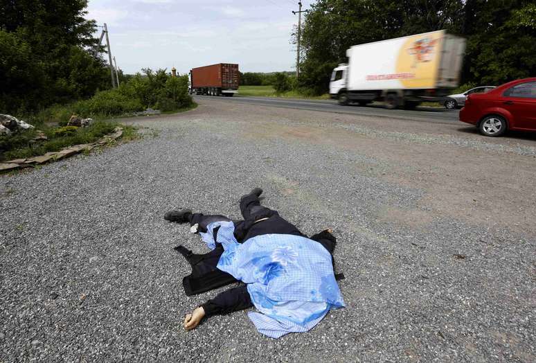 <p>Corpo de um miliciano pró-Ucrânia é visto ao lado de uma estrada após um tiroteio no assentamento rural de Karlovka, oeste de Donetsk, nesta quinta-feira, 23 de maio</p>