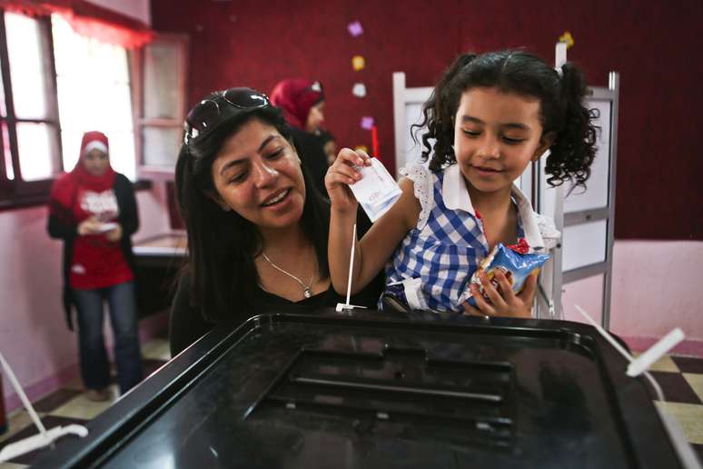 Mulher e criança colocam voto em urna na capital do Egito nesta segunda-feira