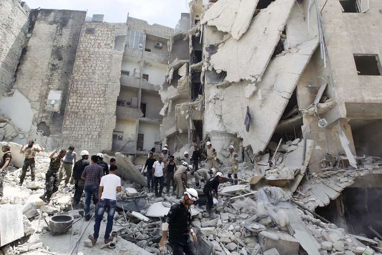<p>Membros da Defesa Civil, rebeldes e civis buscam por sobreviventes em região bombardeada, segundo ativistas, por forças de Bashar al-Assad, em um bairro de Aleppo, em 29 de maio</p>