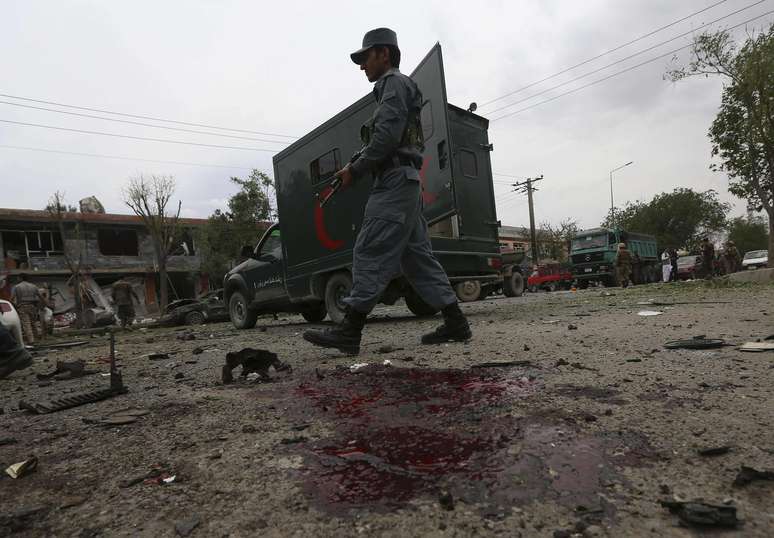 Policial passa em local onde duas bombas explodiram num ataque ao candidato afegão