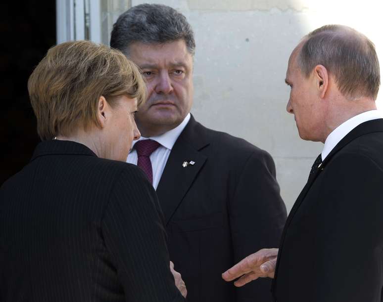 A chanceler alemã, o presidente eleito na Ucrânia e o presidente russo conversam durante encontro de líderes mundiais que participam das cerimônias do Dia D em Benouville, França, nesta sexta-feira
