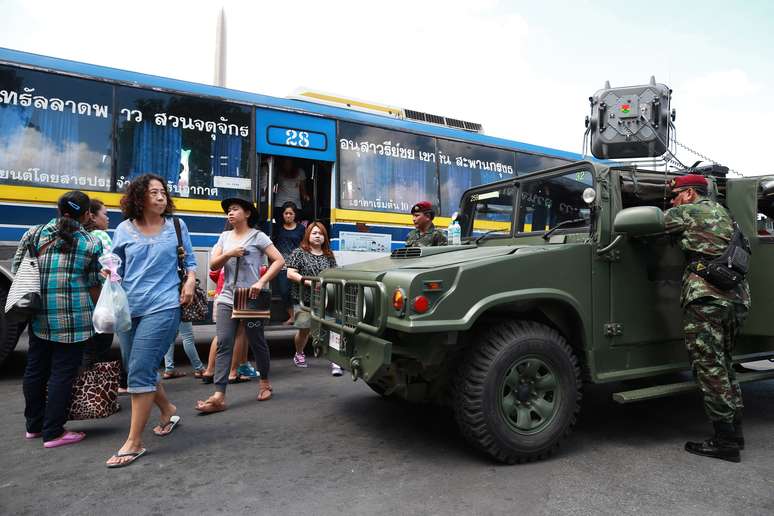 <p>Soldados tailandeses montam guarda enquanto passageiros de um &ocirc;nibus caminham pr&oacute;ximo ao&nbsp;Monumento da Vit&oacute;ria em Bangcoc, em 8 de junho</p>