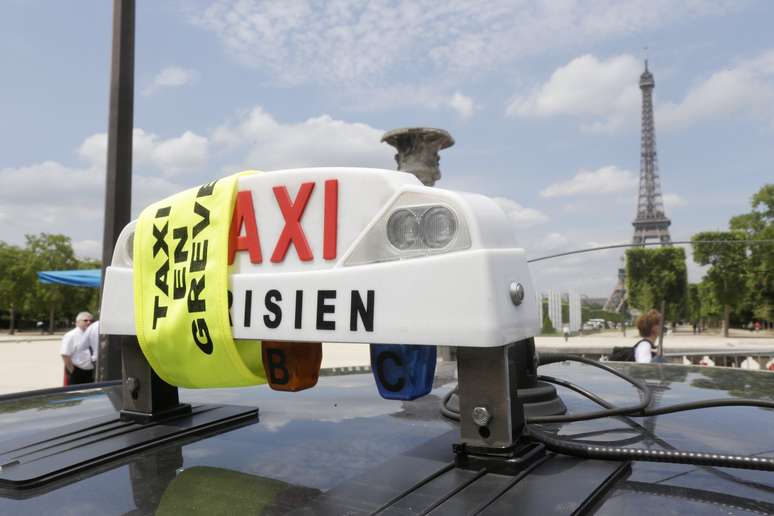 <p>Fitas amarelas colocadas nos veículos sinalizam a participação em uma manifestação de taxistas perto da Torre Eiffel, em Paris, nesta quarta-feira, 11 de junho</p>