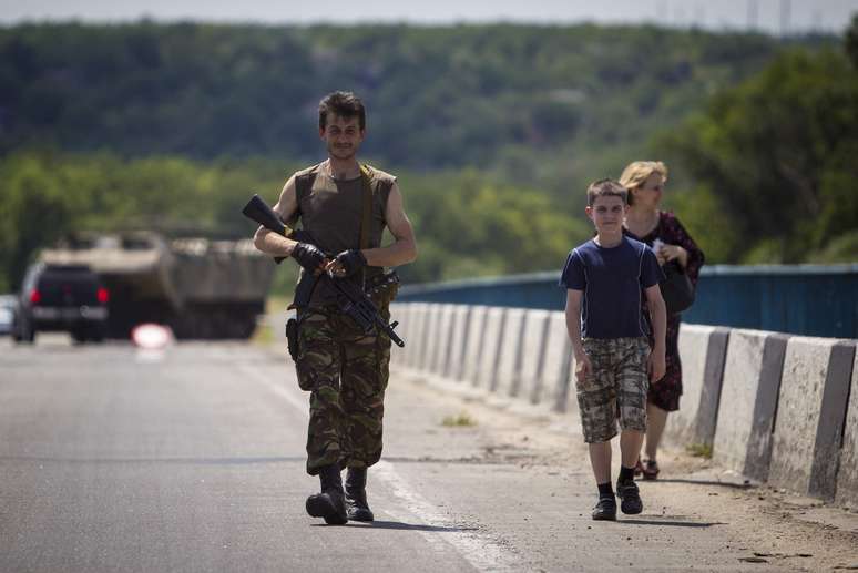 <p>Um militante separatista pr&oacute;-russo &eacute; visto caminhando ao lado de sua fam&iacute;lia em uma rodovia em Lugansk, no leste ucraniano</p>