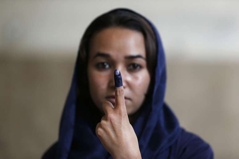 <p>Cerca de sete milhões de eleitores compareceram às urnas para escolher o sucessor do presidente Hamid Karzai. Na foto, mulher mostra o dedo manchado após votar</p>