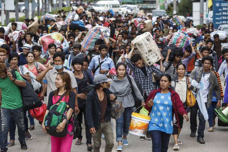 <p>Cambojanos carregam seus pertences enquanto caminham para atravessar a fronteira em Aranyaprathet, em Sa Kaew, Tail&acirc;ndia, em 15 de junho</p>