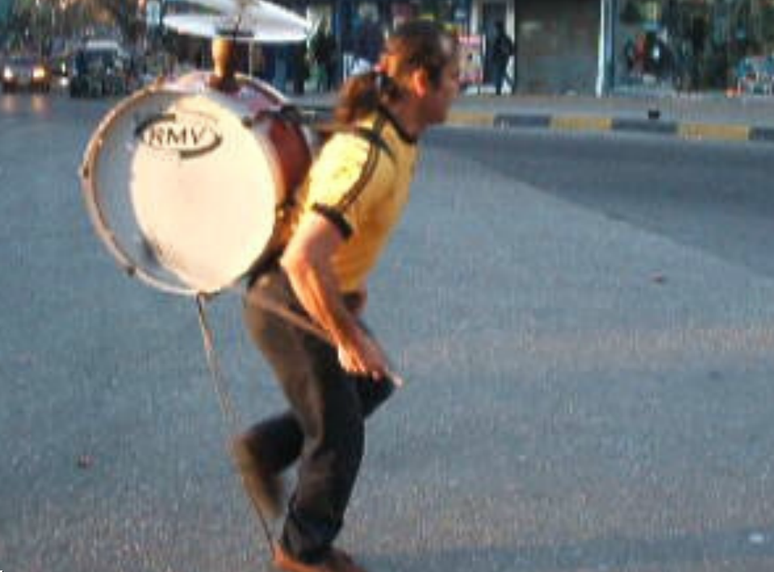 <p>Homem de uma banda só do Chile dança enquanto toca o instrumento conhecido como Chinchinero</p>