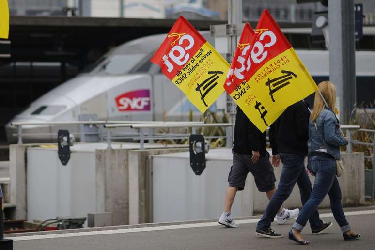 <p>Trabalhadores ferrovi&aacute;rios seguram bandeiras de protesto ao passar em frente a uma esta&ccedil;&atilde;o&nbsp;ferrovi&aacute;ria de Nantes, a oeste da Fran&ccedil;a</p>