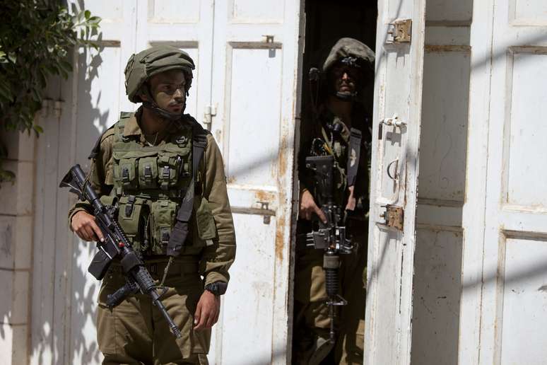 <p>Soldados israelenses entram em uma casa à procura de três adolescentes israelenses desaparecidos, que temem terem sido sequestrados por militantes palestinos, na aldeia de Taffouh perto da cidade de Hebron, nesta quarta-feira, 18 de junho</p>