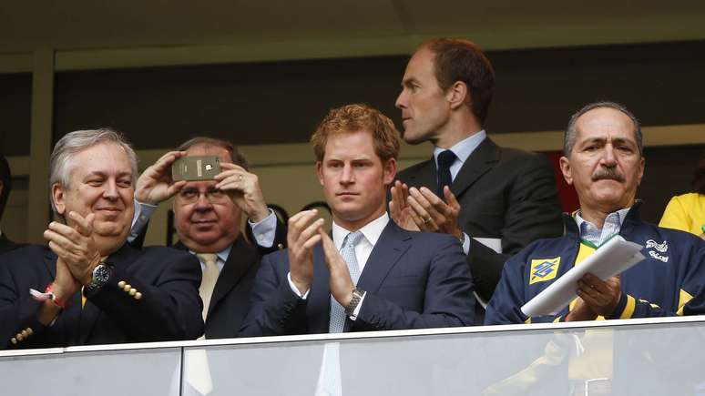 <p>O príncipe Harry, do Reino Unido, acompanha a disputa entre Brasil x Camarões no Estádio Mané Garrincha, em Brasília, nesta segunda-feira; o integrante da família real inglesa segurou uma camisa da Seleção Brasileira e foi clicado ao lado de autoridades como Aldo Rebelo, ministro do Esporte, e José Maria Marin, presidente da CBF </p>