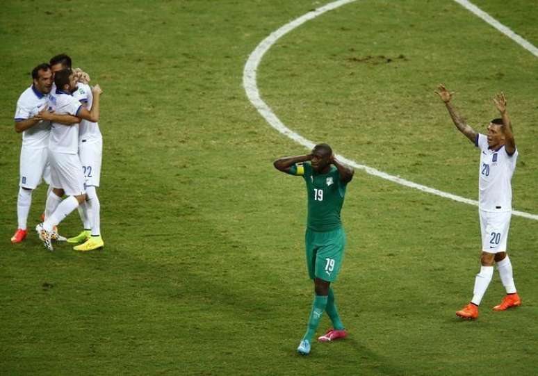 Yaya Toure, da Costa do Marfim, lamenta, enquanto jogadores da Grécia comemoram após partida em Fortaleza. 24/06/2014.