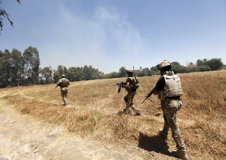 <p>Membros da forças de segurança do Iraque combatem insurgentes do grupo militante sunita Estado Islâmico do Iraque e do Levante na aldeia de Ibrahim bin Ali, a oeste de Bagdá, em 24 de junho</p>