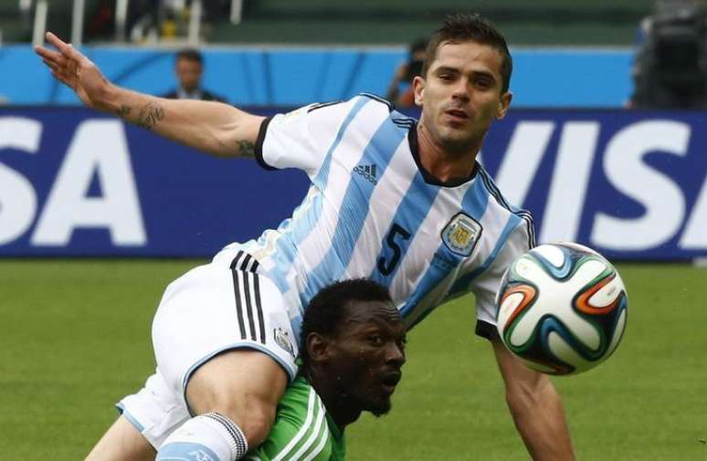 Jogador argentino Fernando Gago (acima) disputa bola com nigeriano Juwon Oshaniwa, durante partida no Estádio Beira-Rio, em Porto Alegre. 25/6/2014