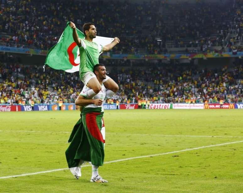 Jogador da Argélia Essaid Belkalem carrega colega Abdelmoumene Djabou após classificação para a oitavas de final em jogo contra a Rússia, na Arena da Baixada, em Curitiba. 26/6/2014