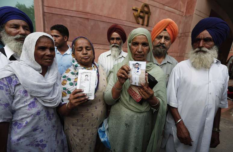 <p>Parentes mostram fotos de trabalhadores indianos que foram sequestrados no Iraque, após uma reunião com o ministro do Exterior da Índia Sushma Swaraj, em Nova Déli, em 19 de junho</p>