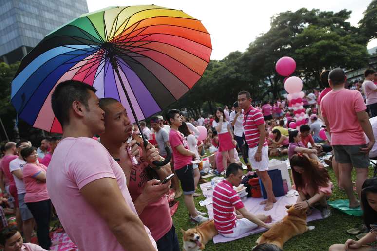 <p>Participantes vestidos de rosa desfrutam de um piquenique antes de tomar parte na formação de um ponto-de-rosa gigante no Hong Lim Park, em Cingapura, em 28 de junho</p>