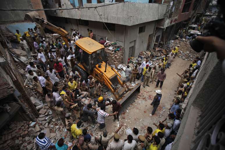 <p>Equipes de resgate retiram o corpo de uma vítima entre os escombros de um edifício que desabou em Nova Deli, Índia, em 28 junho</p>