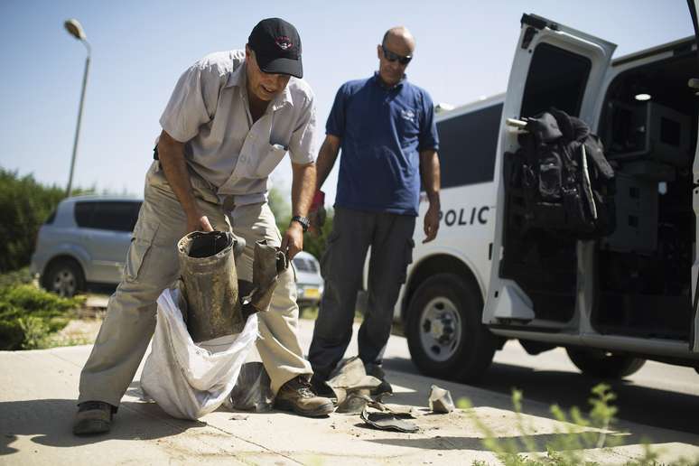 <p>Oficial de seguran&ccedil;a civil israelense recolhe os restos de um foguete que foi disparado a partir de Gaza e caiu em Kfar Maimon, fora do centro da Faixa de Gaza, em 30 de junho</p>