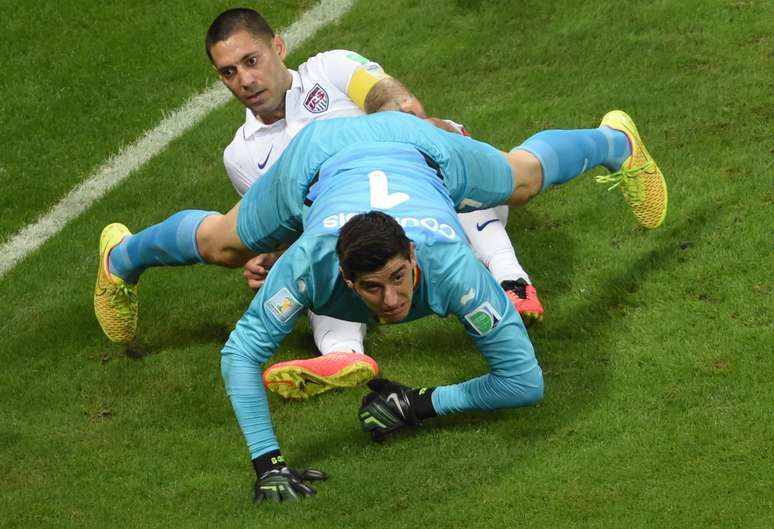 Goleiro belga Thibaut Courtois faz defesa durante disputa com o capitão americano Dempsey