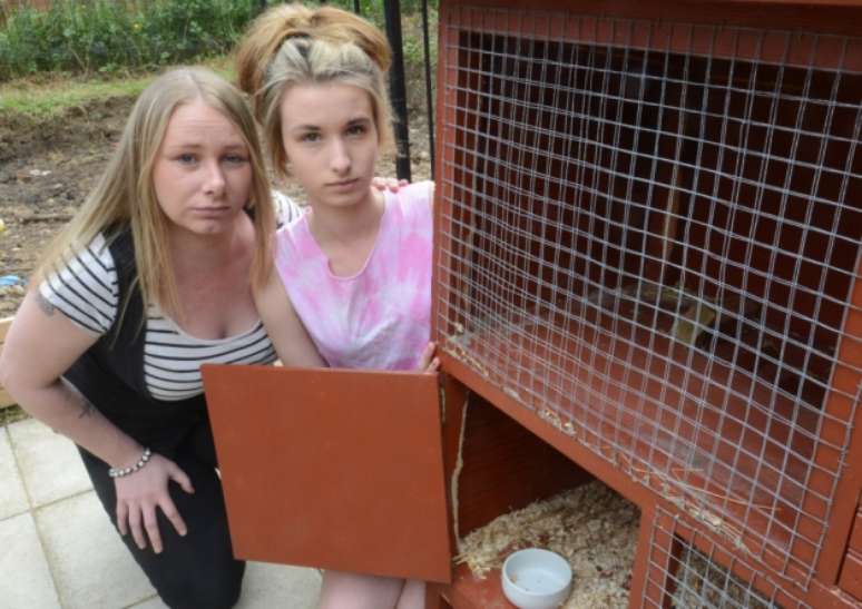 <p>Rebecca Atkinson e sua filha são vistas ao lado da gaiola vazia da coelha Percy</p>