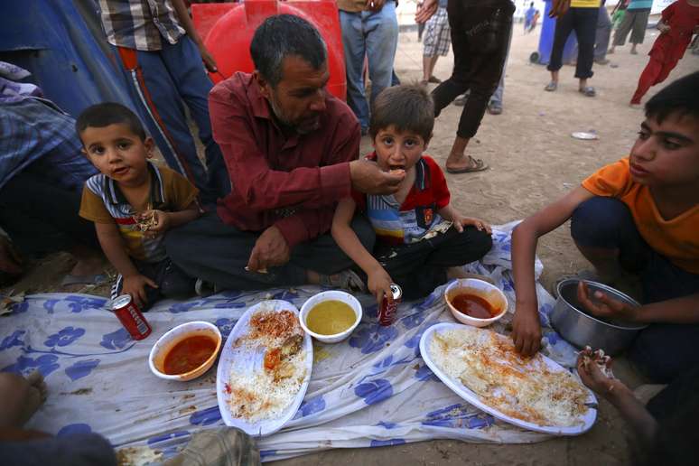 <p>Refugiados iraquianos que deixaram Mossul fazem refeição no interior do campo de refugiados Khazer na periferia de Arbil, na região do Curdistão, em 29 de junho</p>