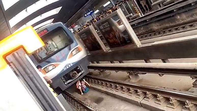 <p>Um usuário do metrô registrou o momento em que Yue Yan Mai se abaixa para tentar sair de debaixo do trem</p>