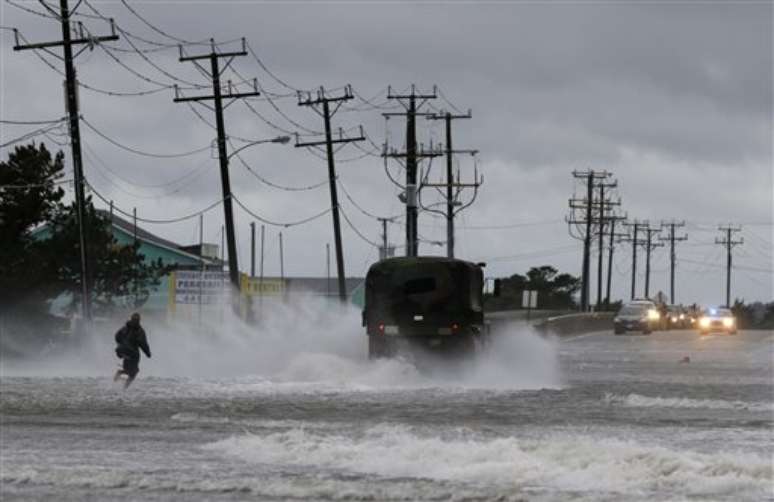 <p>Veículo militar e um homem em estrada inundada por conta da passagem do furacão Arthur</p>