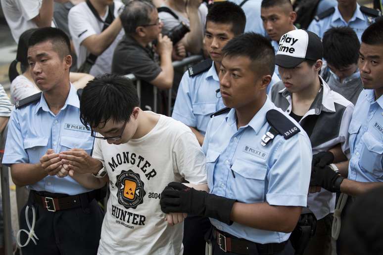 <p>Manifestantes s&atilde;o levados&nbsp;por policiais depois de passarem uma noite detidos no distrito financeiro central de Hong Kong, em&nbsp;2 de julho</p>