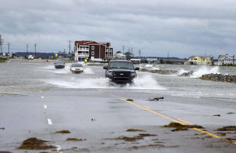 <p>Carros cruzam uma avenida alagada ap&oacute;s a passagem do furac&atilde;o Arthur em Nags Head, na Carolina do Norte, Estados Unidos, nessa sexta-feira</p>