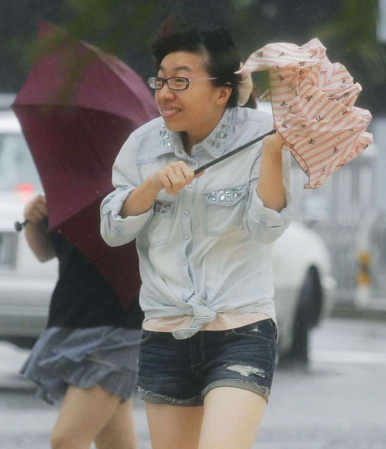 <p>Uma mulher segurando um guarda-chuva anda contra os fortes ventos trazidos pelo tufão Neoguri em uma rua de Naha, em Okinawa, em 8 de julho</p>