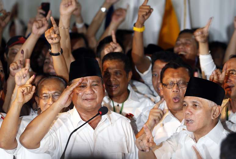 <p>Candidato presidencial da Indon&eacute;sia, Prabowo Subianto (&agrave; direita) d&aacute; uma sauda&ccedil;&atilde;o, ao lado de sua equipe&nbsp;e apoiadores, ap&oacute;s declarar vit&oacute;ria em Jacarta, nesta quarta-feira,&nbsp;9 de julho</p>