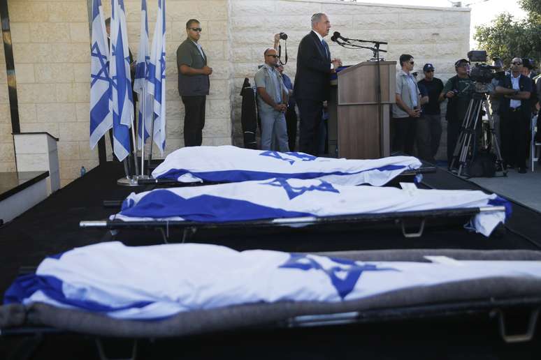 <p>O primeiro-ministro israelense, Benjamin Netanyahu (ao fundo), discursa durante funeral dos tr&ecirc;s adolescentes&nbsp;israelenses sequestrados e mortos na Cisjord&acirc;nia, em 1&ordm; de julho</p><p>&nbsp;</p>
