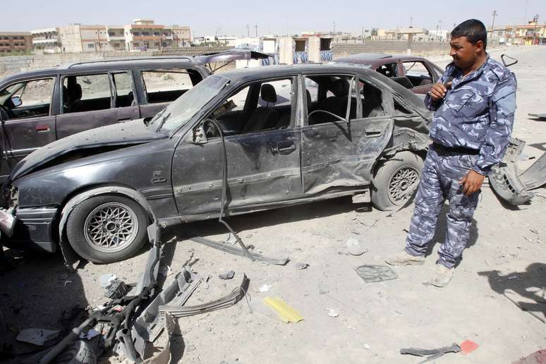 <p>Um policial inspeciona os danos causados a alguns veículos após um ataque com um carro-bomba perto de uma delegacia de polícia, ao sul da cidade de Kirkuk, em 10 de julho</p><p> </p>