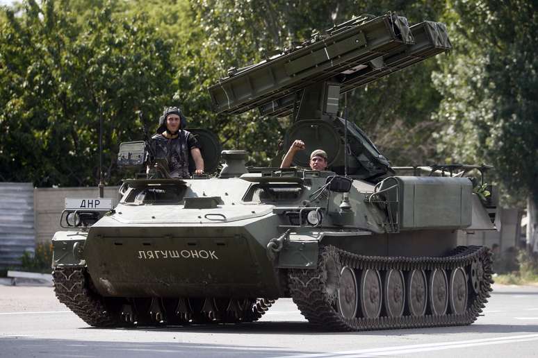 <p>Pr&oacute;-russos acenam dentro&nbsp;de um lan&ccedil;ador de m&iacute;sseis blindado em um posto de controle na periferia da cidade ucraniana de Donetsk, em&nbsp;10 de julho</p>