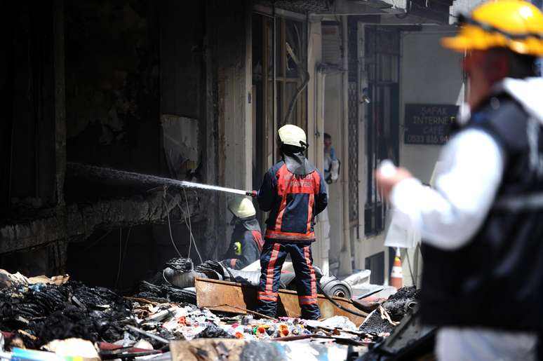 <p>Um bombeiro turco extingue um incêndio após uma explosão de gás ocorrida em um prédio, no distrito de Zeytinburnu, em Istambul, neste sábado, 12 de julho</p>