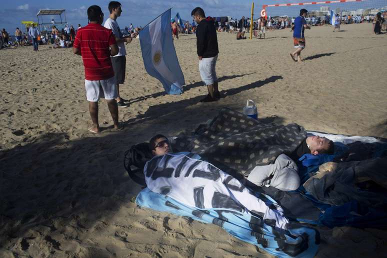 <p>Antes da final entre Argentina e Alemanha, torcedores dormiram na praia de Copacabana, no Rio de Janeiro, enrolados em cobertores e bandeiras. A final da Copa do Mundo acontece neste domingo, no Estádio do Maracanã</p>