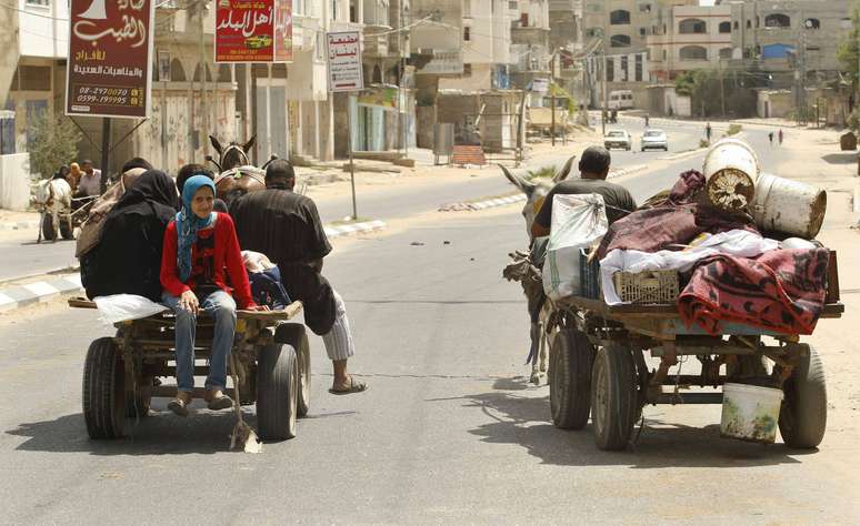 <p>Palestinos, que fugiram de suas casas,&nbsp;adjacentes &agrave; fronteira com Israel, andam&nbsp;de carro&ccedil;a e seguem para&nbsp;uma escola das Na&ccedil;&otilde;es Unidas, no norte da Faixa de Gaza, neste domingo, 13 de julho</p>