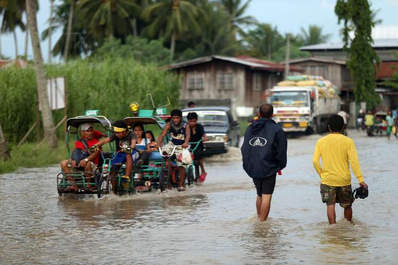 <p>Moradores cruzam&nbsp;uma estrada inundada em Mindanao, nas Filipinas, em&nbsp;15 de julho</p>