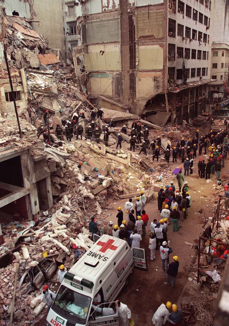 <p>Bombeiros e equipes de resgate procuram sobreviventes entre os escombros do centro da Comunidade Judaica em Buenos Aires, depois de um carro-bomba destruir o edifício em 18 de julho de 1994</p>